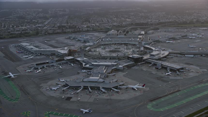 A stunningaerial footage capturing the breathtaking sunset as it flies by and away from San Francisco International Airport showcasing the bustling aviation and transportation hub set against the scenic backdrop of the San Francisco Bay Area in Northern C