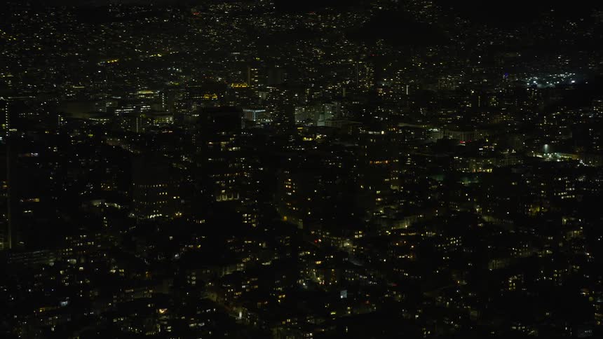 Aerial footage of illuminated apartment and office buildings in the metropolitan cityscape of San Francisco's Nob Hill neighborhood at night during summer
