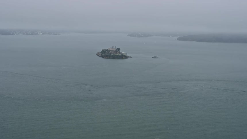 Approaching Alcatraz Island on a foggy day in northern California showcasing the iconic historic landmark of the Alcatraz federal penitentiary from a wide angle perspective