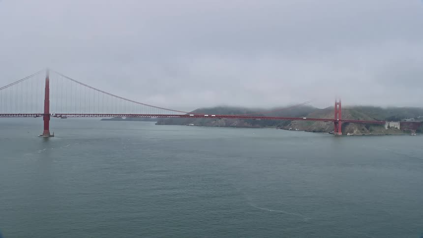  aerial footage of the iconic Golden Gate Bridge on a foggy day showcasing the historic landmark and picturesque view of San Francisco Bay from a side view