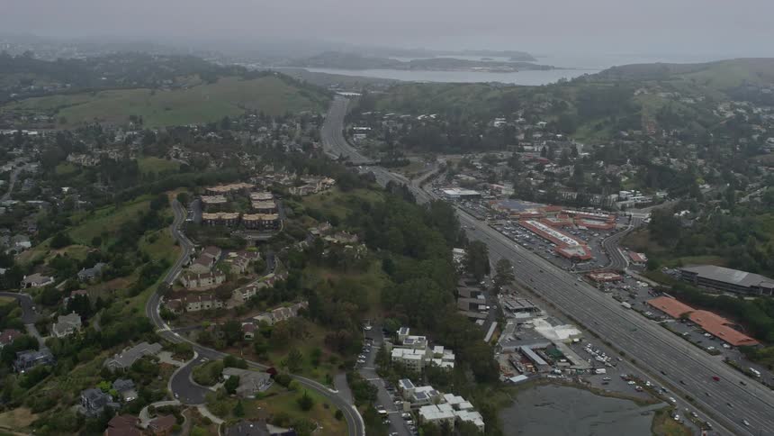  aerial footage captures Highway 101 cutting through Mill Valley on a foggy day showcasing the urban landscape and residential apartment buildings