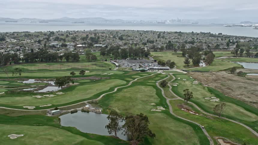  aerial flyover showcasing a golf course in Alameda California with a tilt down to a parking lot on a cloudy day
