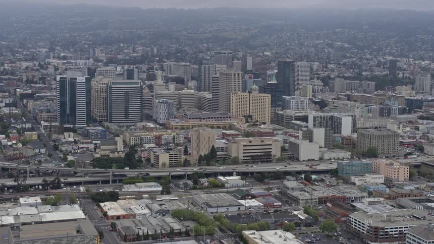 Approaching Downtown Oakland on a foggy day California with office buildings industry and a cityscape emerging from the overcast skies