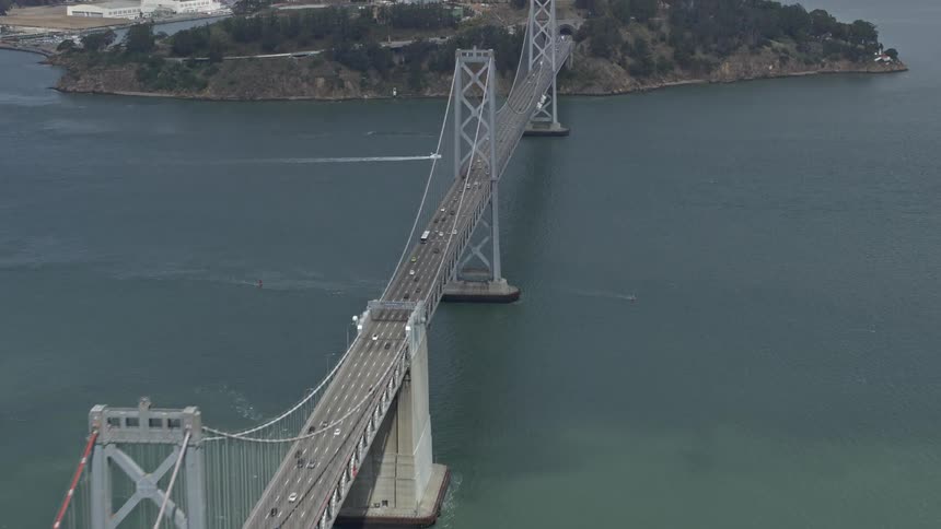 Aerial footage of light traffic on the Bay Bridge near Yerba Buena Island San Francisco as seen from a side view on a sunny day