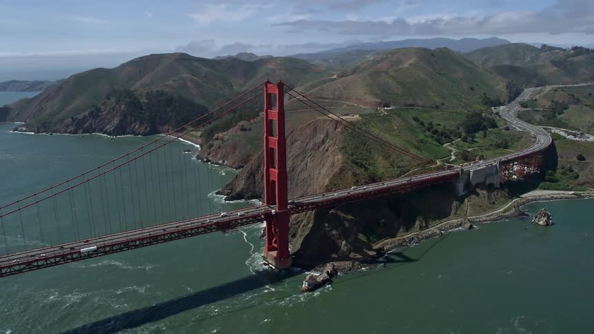 Aerial footage of a partly cloudy day circling one of the iconic towers on the Golden Gate Bridge in San Francisco California