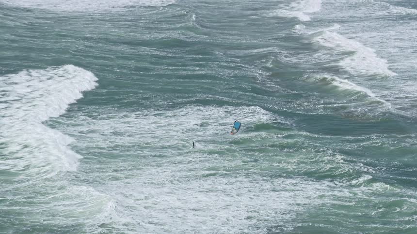  aerial footage of a kite surfer riding the waves near the Outer Sunset District San Francisco California capturing the thrilling and adventurous sport of kite surfing in the beautiful coastal scenery of Northern California's Bay Area during a partly clou
