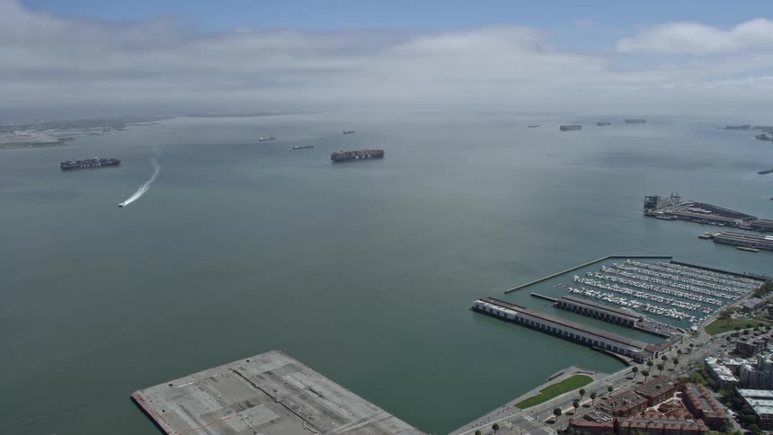 Aerial footage of cargo ships approaching and sailing in San Francisco Bay California on a partly cloudy day showcasing the maritime nature of the area