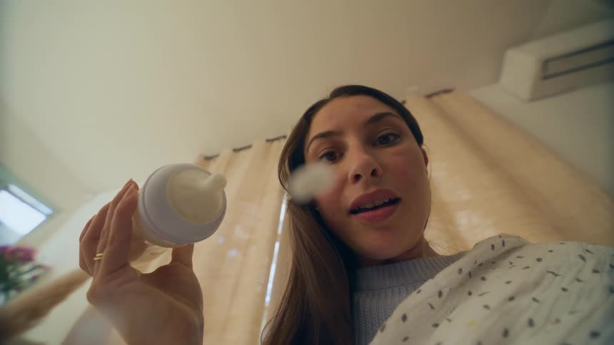 A woman holding bottle for a baby gets surprised by the bottle leaking