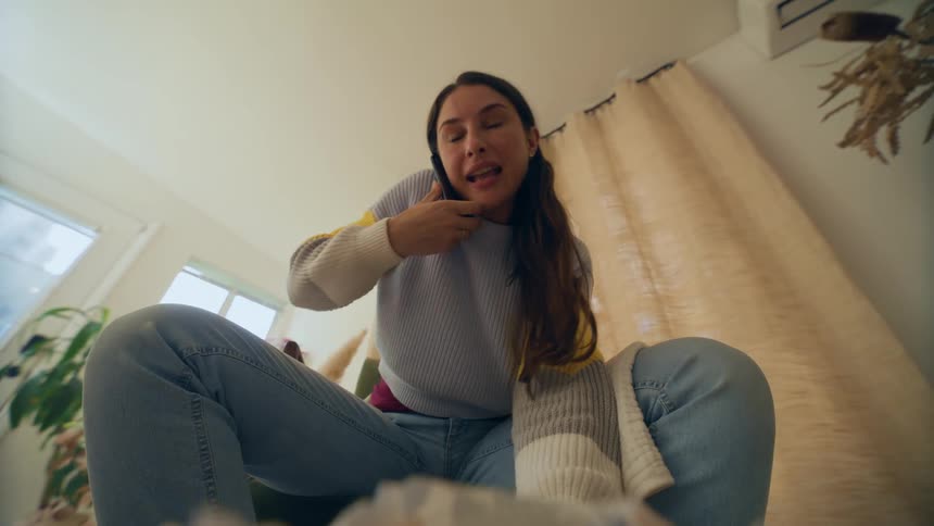 Woman talking on the phone sitting and wiping her hand on a rag