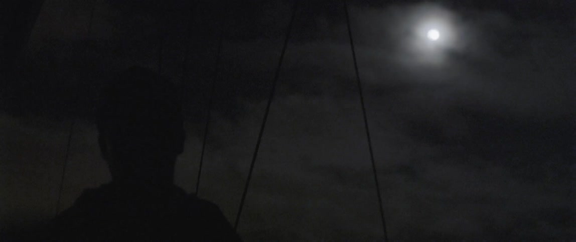 A man is standing outside under a full moon