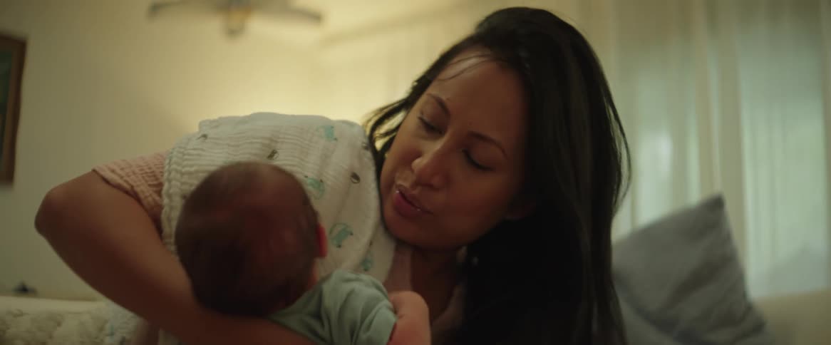 Mother kiss and holds her baby in the couch at home