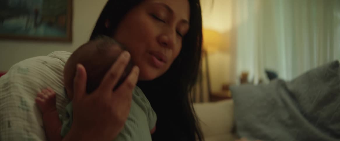 A woman cradles a young baby against her shoulder while patting its back