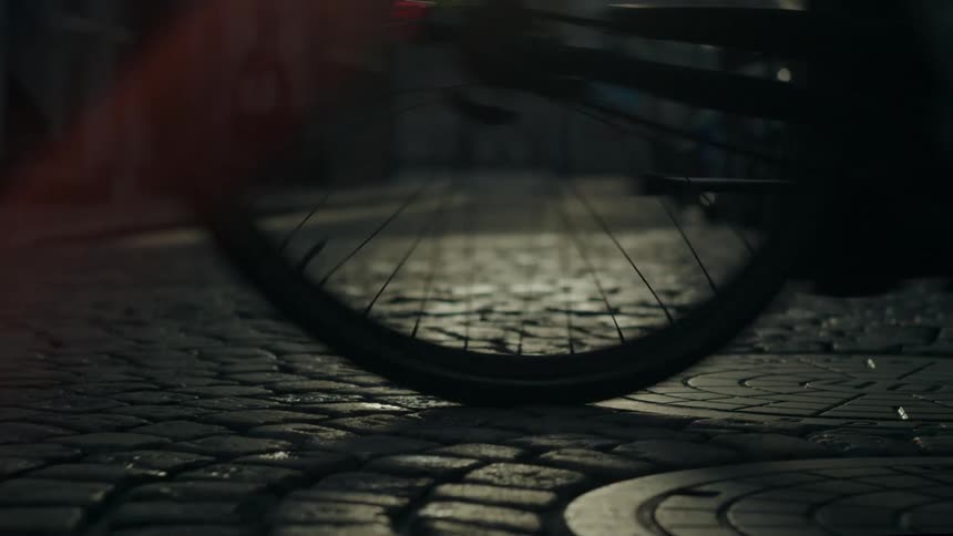 Wheels of a bicycle driving over a cobblestone street