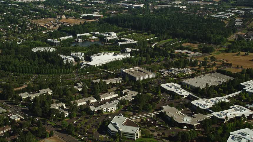 Aerial view of Nike Headquarters surrounded by woods and a lake located in Beaverton Oregon with parking lots curving around the building complex