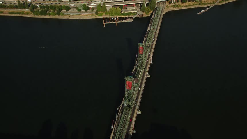 Bird's eye view aerial footage of the Steel Bridge spanning the Willamette River in Downtown Portland Oregon on a sunny day