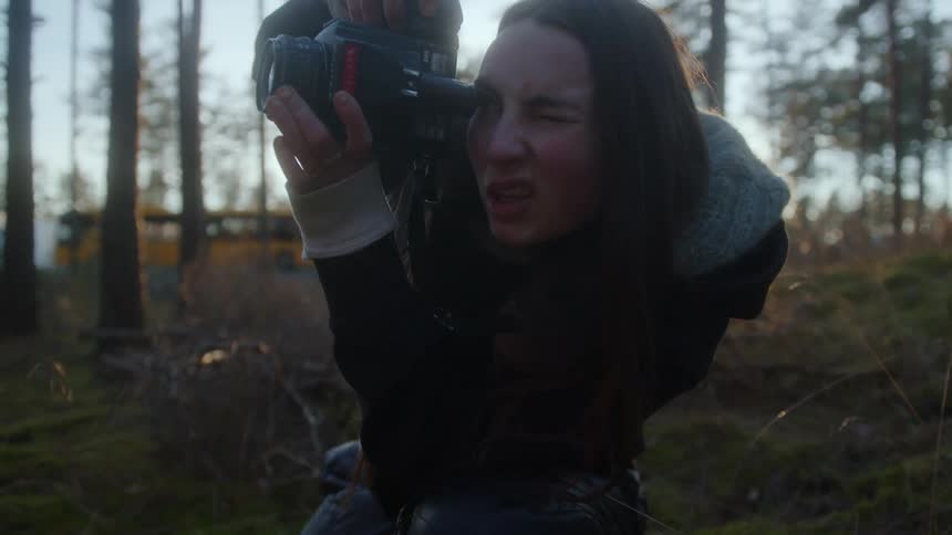 A woman crouched on the side of a road with a camera in her eyes and too focused to take the picture