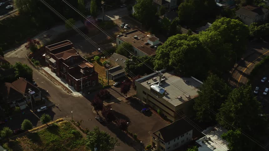Aerial footage of gondolas tracking over city streets in Southwest Portland Oregon on a sunny day