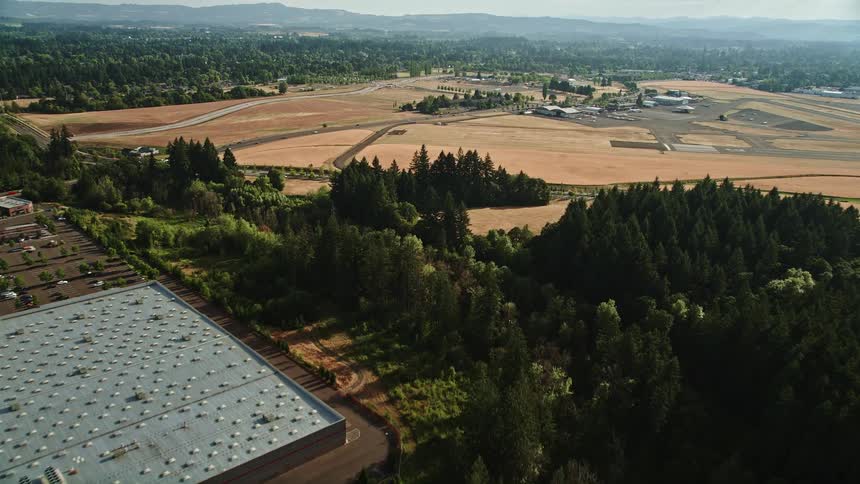Aerial view of trees and fields as a drone approaches parked aircraft at Hillsboro Airport in Oregon