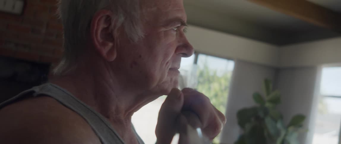 An elderly man is working out inside of his home