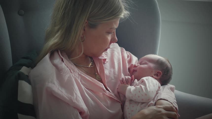 A mother rocks her baby in the seat