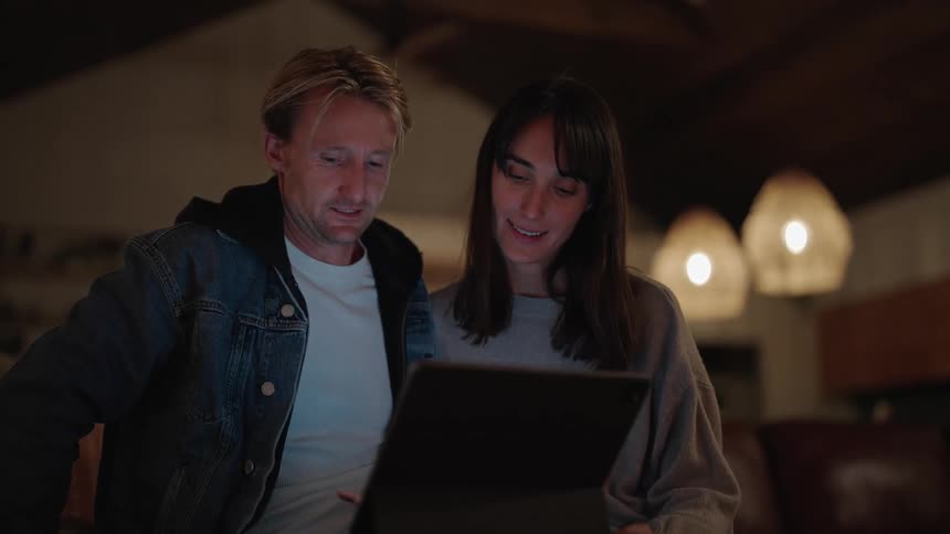 A man and woman talking while looking at a bright computer screen
