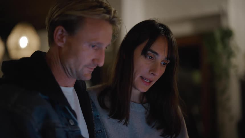 A man and woman are together while they look at the screen of an electronic device