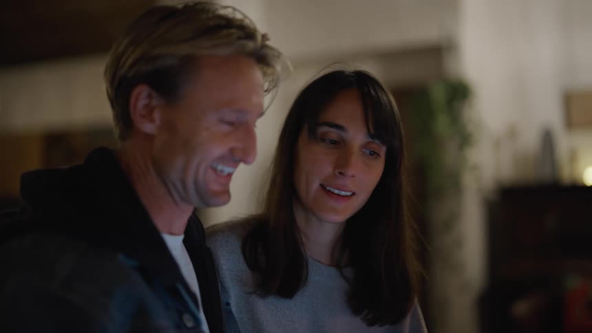 A man and woman smile while having a lively conversation indoors