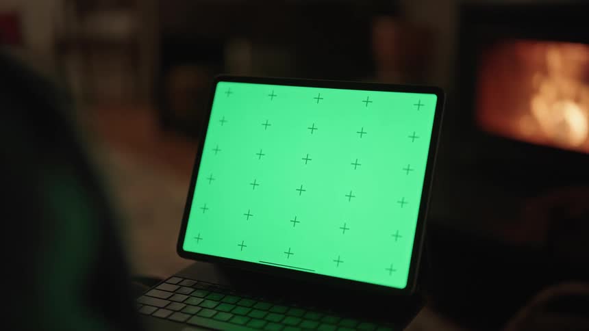 A womans hand points at a laptops monitor showing a green screen