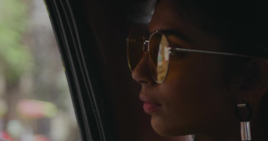 Woman looks out window while riding in vehicle through busy city