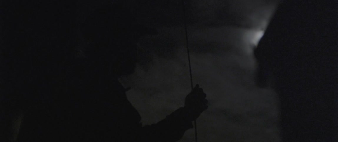 A man is hanging onto a rope on a cloudy night
