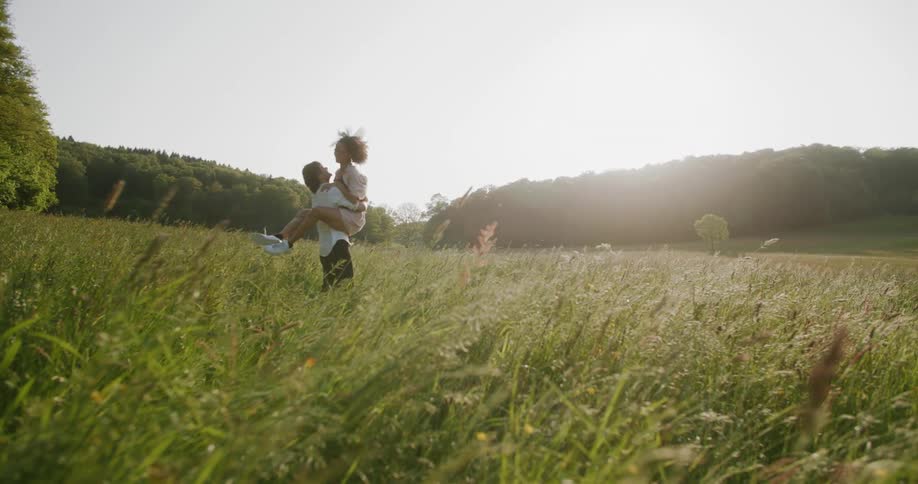 A man and woman couple run across a field to embrace