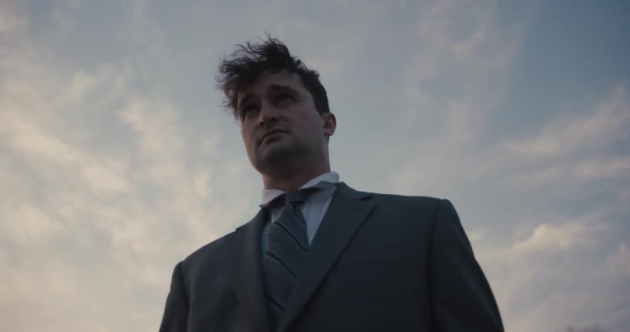 A businessman in a suit stares at the horizon with concern