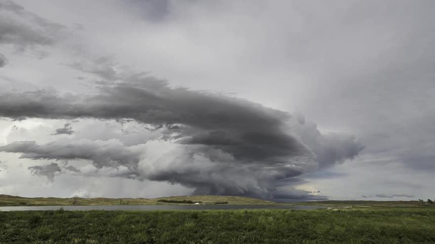 A large storm cloud passing quickly over a field