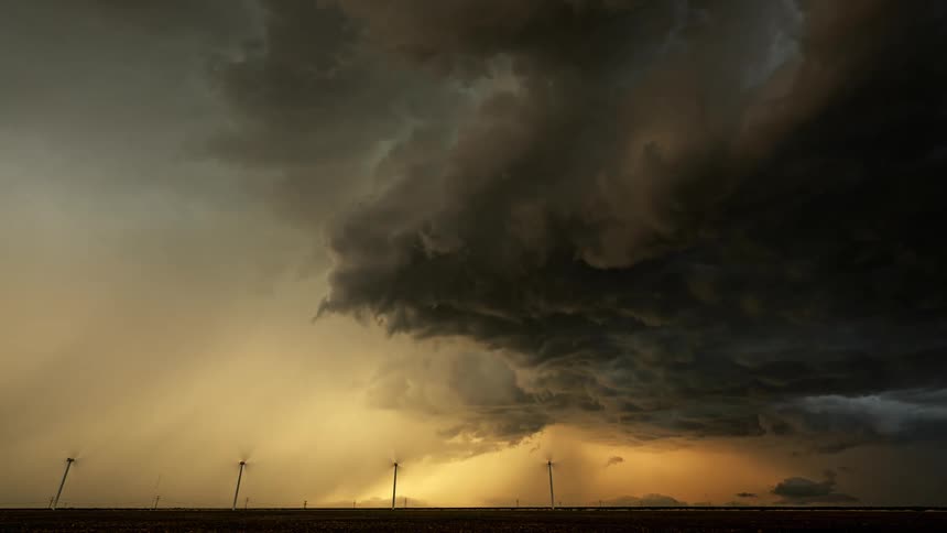 Four windmills under a cloudy sky with lightning