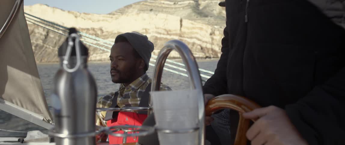 A man is sitting while another steers the boat
