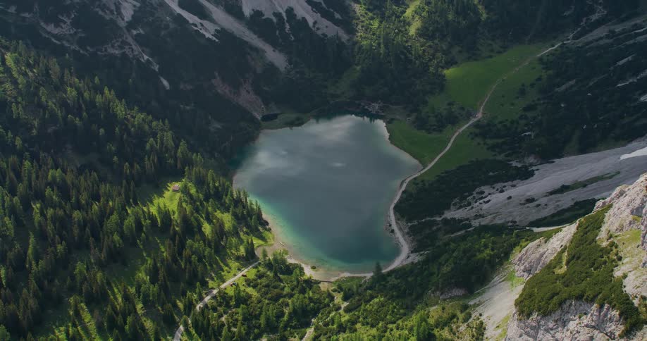 Road winds through narrow valley and through forest passing lake
