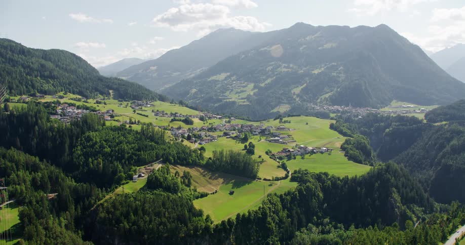 Drone view of a rural village with houses and buildings across the landscape with mountains in the background