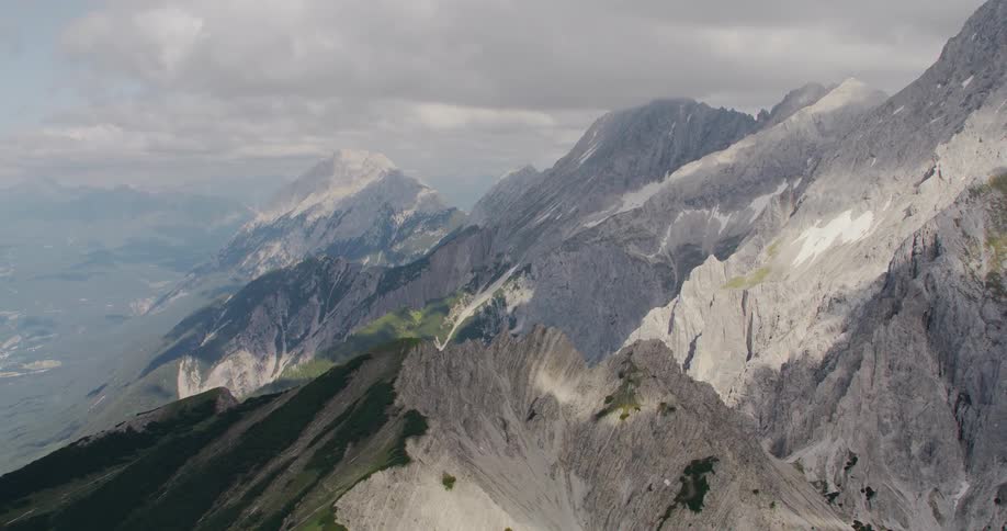 Snow covers jagged mountains in mountain range on foggy and overcast day