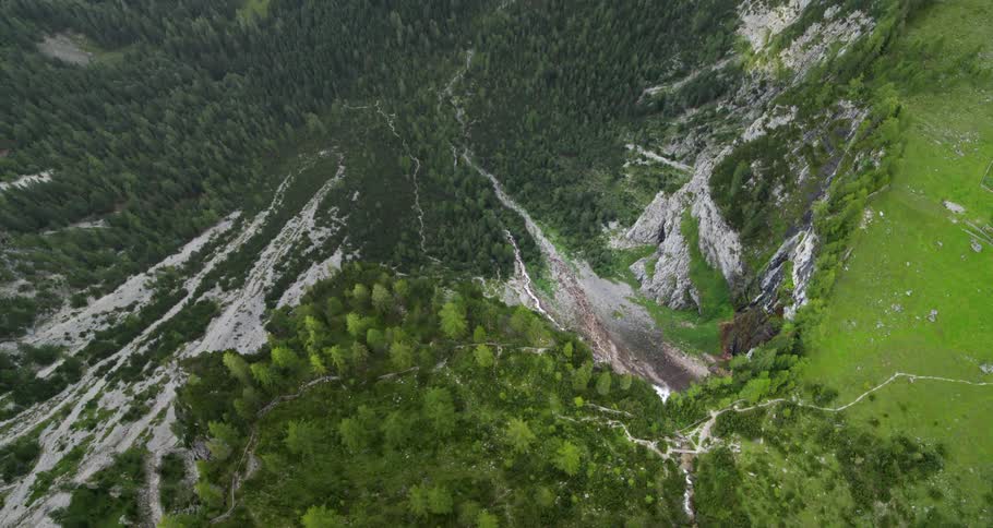 A steep rocky cliff leads down to a forested valley beneath it