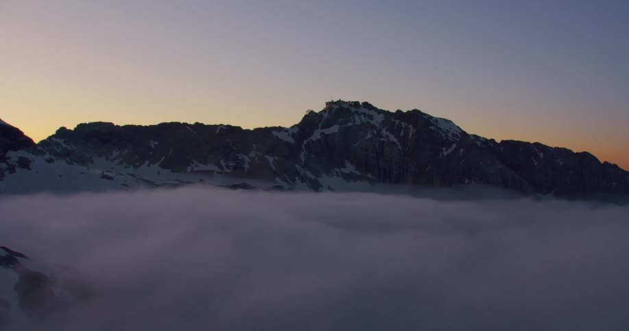 Aerial of a snow covered mountain at cloudy dawn