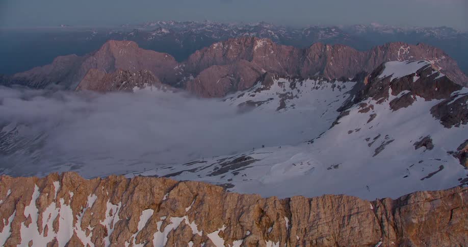 An aerial view of a snowy valley surrounded by mountain ridges