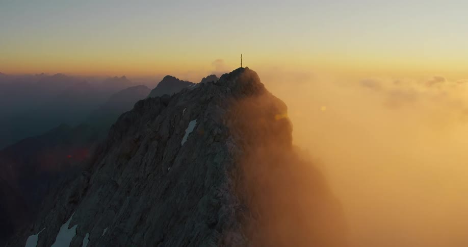 A breathtaking view of mountains with a smoky cloud gently moving through the evening sky