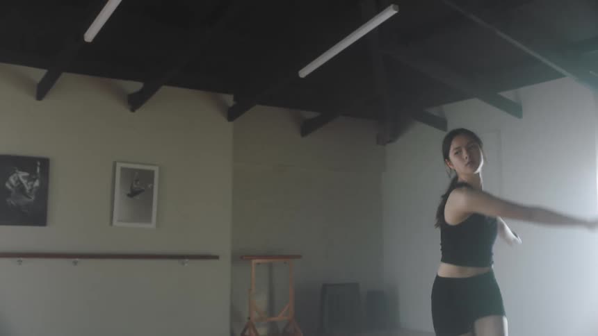 A young woman practices various dance moves while alone