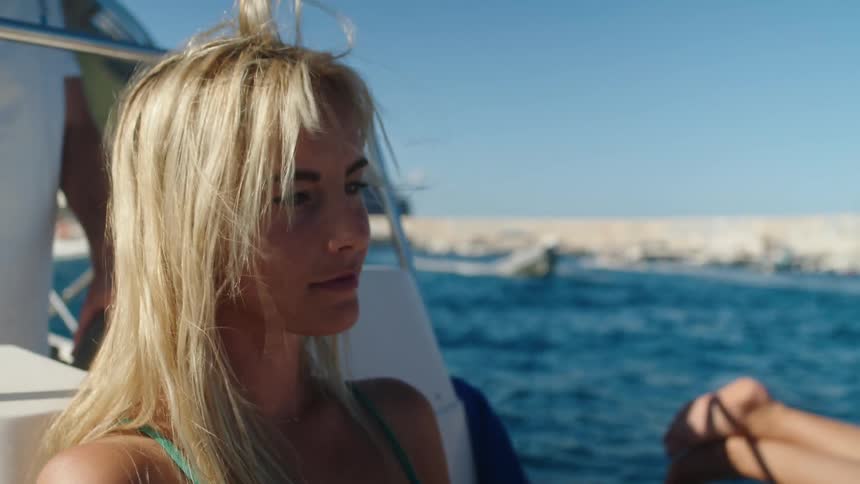 Close up of a young woman with an expression of happiness sitting on a yacht in the open sea
