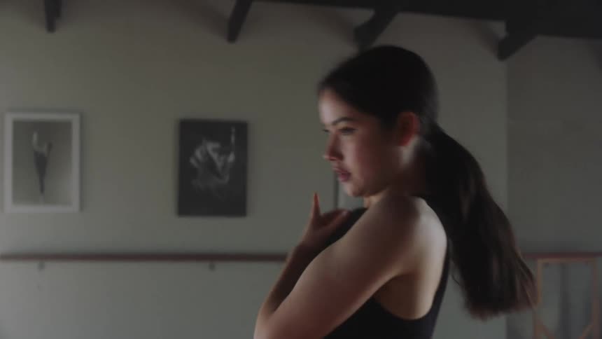 A young girl dancing in a room with picture frame while wearing black short