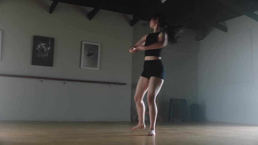 A ballerina dancer practicing her dance move while wearing black short in a room with wall frame