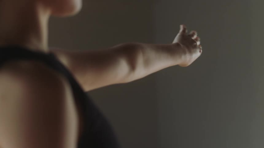 A young girl in a room pointing her hand forward and twisting the hand