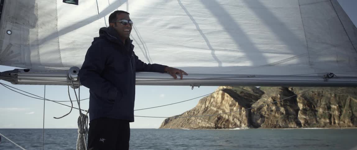 A man is leaning against the sale of a boat laughing