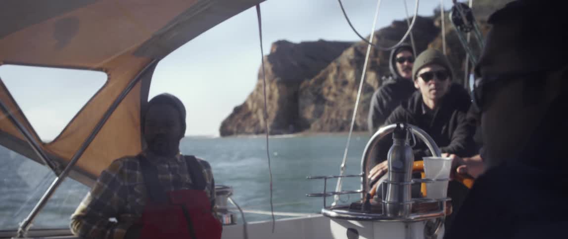 People talk on a boat as one person steers with the wheel