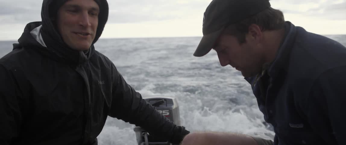 Two men talk while sitting on a moving raft
